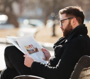 Persona leyendo un periódico en el banco